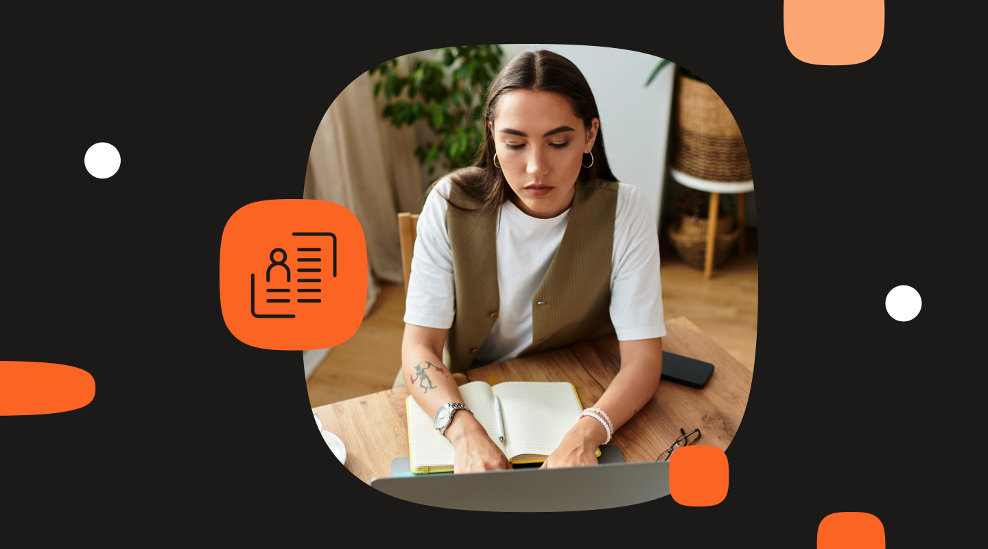 A young woman sits at a wooden desk working on a laptop with a notebook open in front of her. The background is black with orange and white graphic shapes and an orange icon showing a customer profile card, suggesting customer data or identity management.