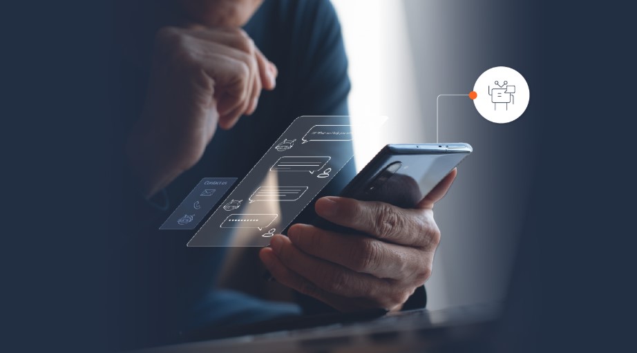 Persona sosteniendo un teléfono móvil con una interfaz de chat holográfica y una burbuja de conversación, destacando un chatbot.