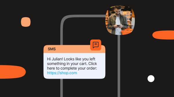 An SMS example that says: "Hi Julian! Looks like you left something in your cart. Click here to complete your order: https://shop.com ". There is an image of a person in a store holding a mobile phone next to a shopping basket.