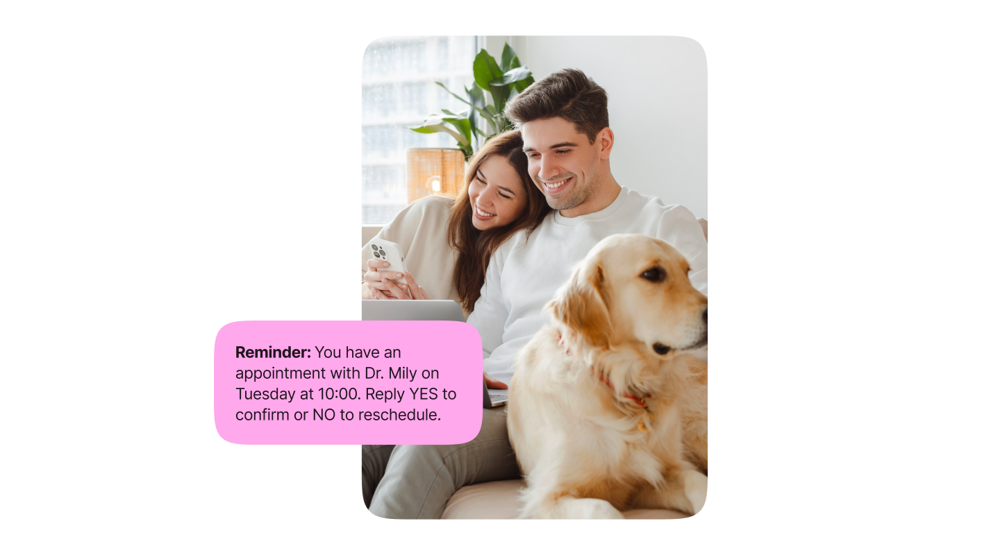 A happy couple and a dog relaxing and reading a message: Reminder - you have an appointment with Dr. Mily on Tuesday at 10AM. Reply YES to confirm and NO to reschedule.