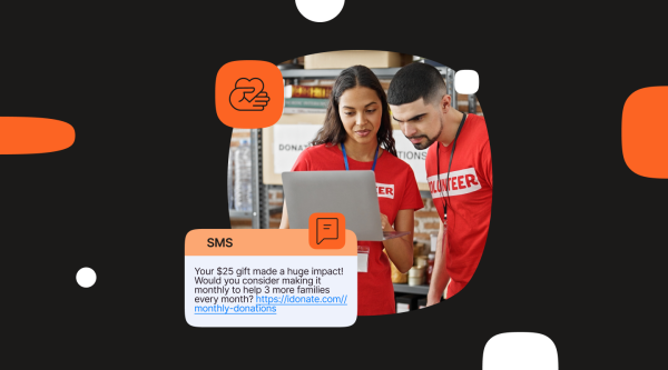 Two volunteers wearing red shirts labeled “VOLUNTEER” look at a laptop together in a donation center. A sample SMS fundraising message is displayed, thanking a donor for a $25 gift and encouraging a recurring monthly donation.