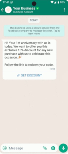 Captura de tela de um chat no WhatsApp. No topo, título "Your Business" com ícone verde. A tela mostra uma conversa com uma mensagem automática oferecendo 10% de desconto para o aniversário da empresa, instruções para resgatar o código e um botão "GET DISCOUNT". Abaixo, a barra de digitar mensagem com ícone de anexo e microfone.