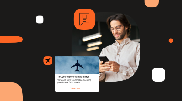A person wearing a light-colored shirt is holding a smartphone. Next to them is a notification showing a flight boarding pass with an airplane icon. The message reads, "Tim, your flight to Paris is ready! View and save your mobile boarding pass below. Safe travels!" with a "View pass" link.
