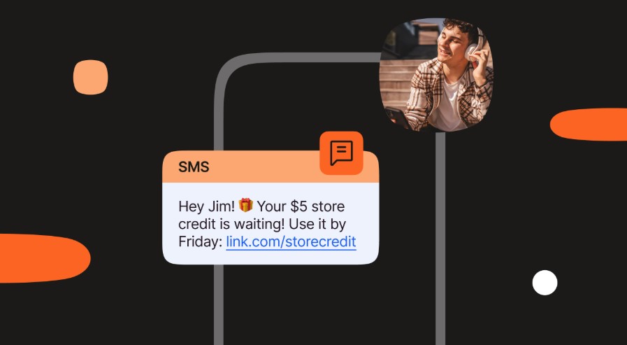 Imagem de um celular estilizado em um fundo escuro com formas geométricas em laranja. Na tela do celular, há uma notificação de SMS que diz: "Olá, João! 🎁 Seus R$30 de crédito estão te esperando! Use até sexta-feira: link.com/storecredit". No canto superior direito da imagem, há um círculo que mostra o rosto de um homem sorrindo, usando fones de ouvido e segurando um celular.