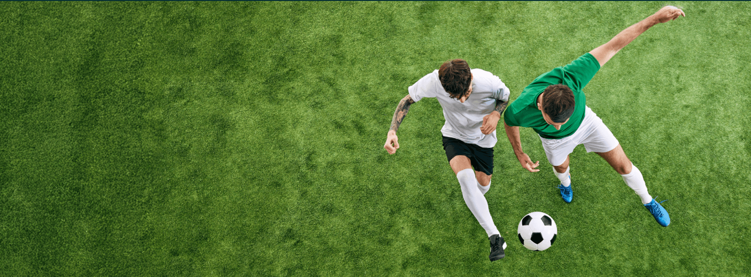 Aerial view of two football players contesting for the ball on a vibrant green pitch, with white tactical markings overlaid illustrating player positions and movement.