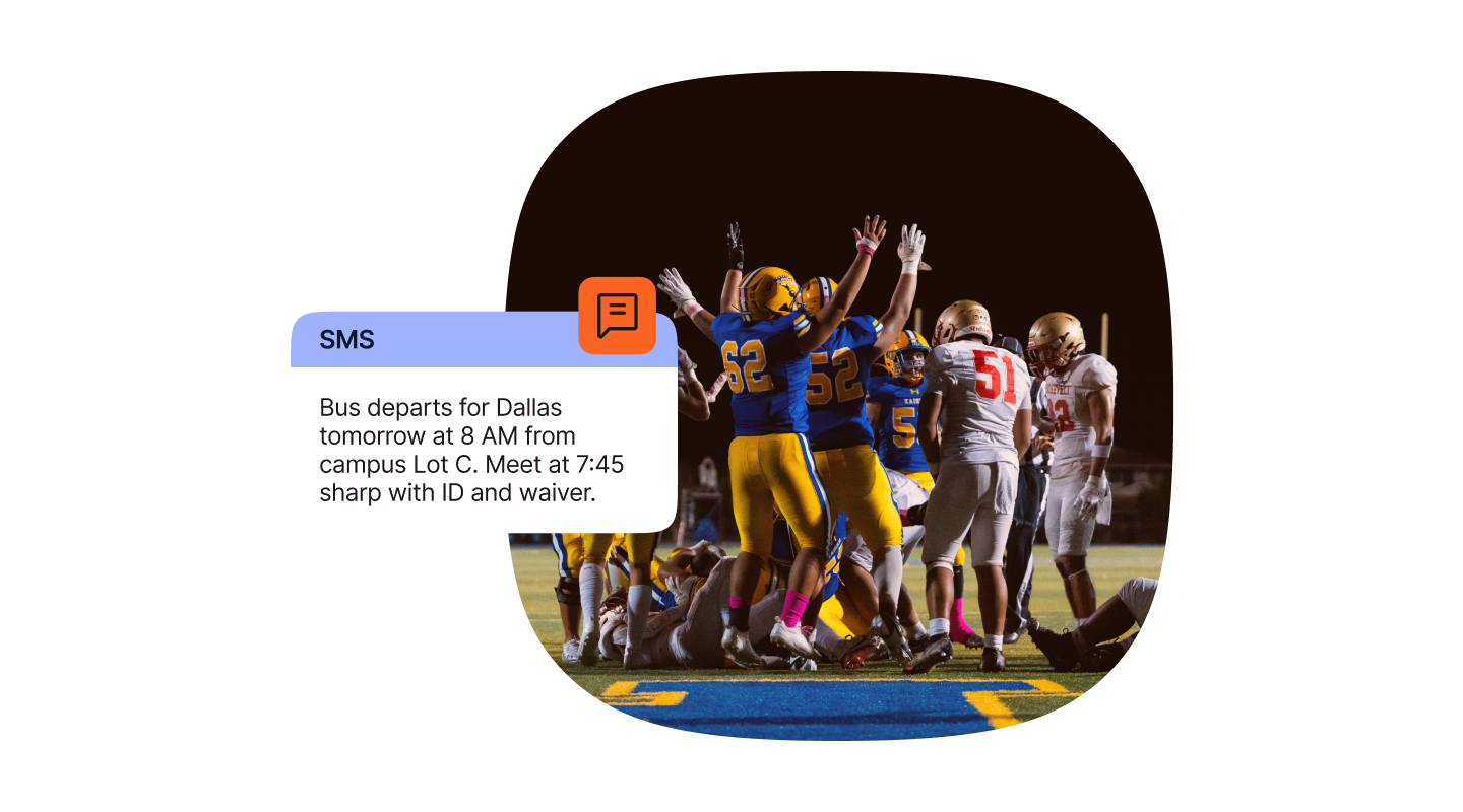 A nighttime scene on a football field with players from two teams gathered near the end zone. Players in blue and yellow uniforms are strongly celebrating with raised arms, while opponents in white and red uniforms are close by. Stadium lights illuminate the field, and the grass is clearly visible. An SMS notification icon in orange is displayed on the left with a message about a bus departure for Dallas tomorrow at 8 AM from campus Lot C, advising the group to meet at 7:45 sharp with ID and waiver in hand.