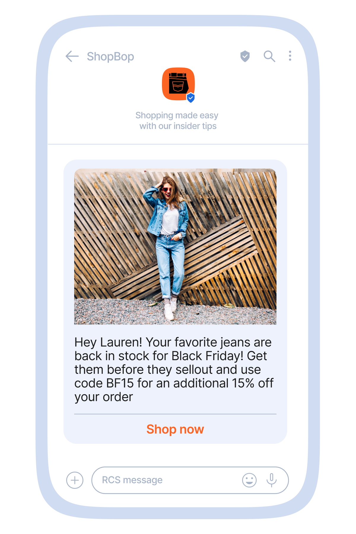 Mobile messaging mockup showing a promotional conversation with a fashion brand called “ShopBop.” The message card features a photo of a person standing in front of a modern wooden slat wall, wearing a denim jacket, jeans, and white sneakers. Below the image, text reads: “Hey Lauren! Your favorite jeans are back in stock for Black Friday! Get them before they sellout and use code BF15 for an additional 15% off your order.” A prominent orange “Shop now” button appears at the bottom of the card.