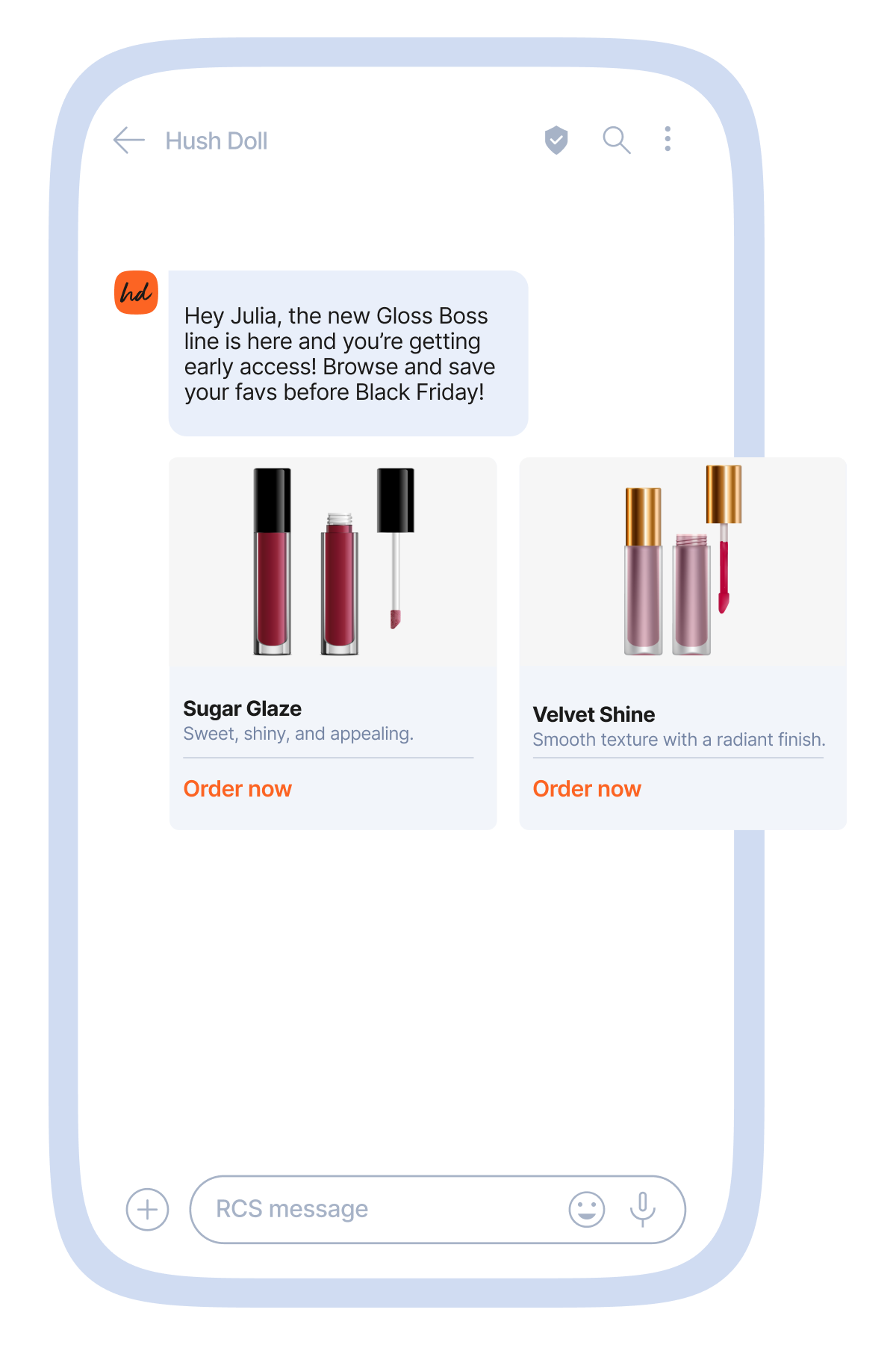 Mobile messaging mockup showing a promotional conversation with a beauty brand called “Hush Doll.” A message says, “Hey Julia, the new Gloss Boss line is here and you’re getting early access! Browse and save your favs before Black Friday!” Below, two rich cards display lip gloss products: “Sugar Glaze,” described as sweet, shiny, and appealing, with red gloss tubes, and “Velvet Shine,” described as having a smooth texture with a radiant finish, with pink gloss tubes. Each card includes an “Order now” button, and the first card also has an “Ask our chatbot” button. The interface appears inside a light blue smartphone frame with standard chat input icons at the bottom.