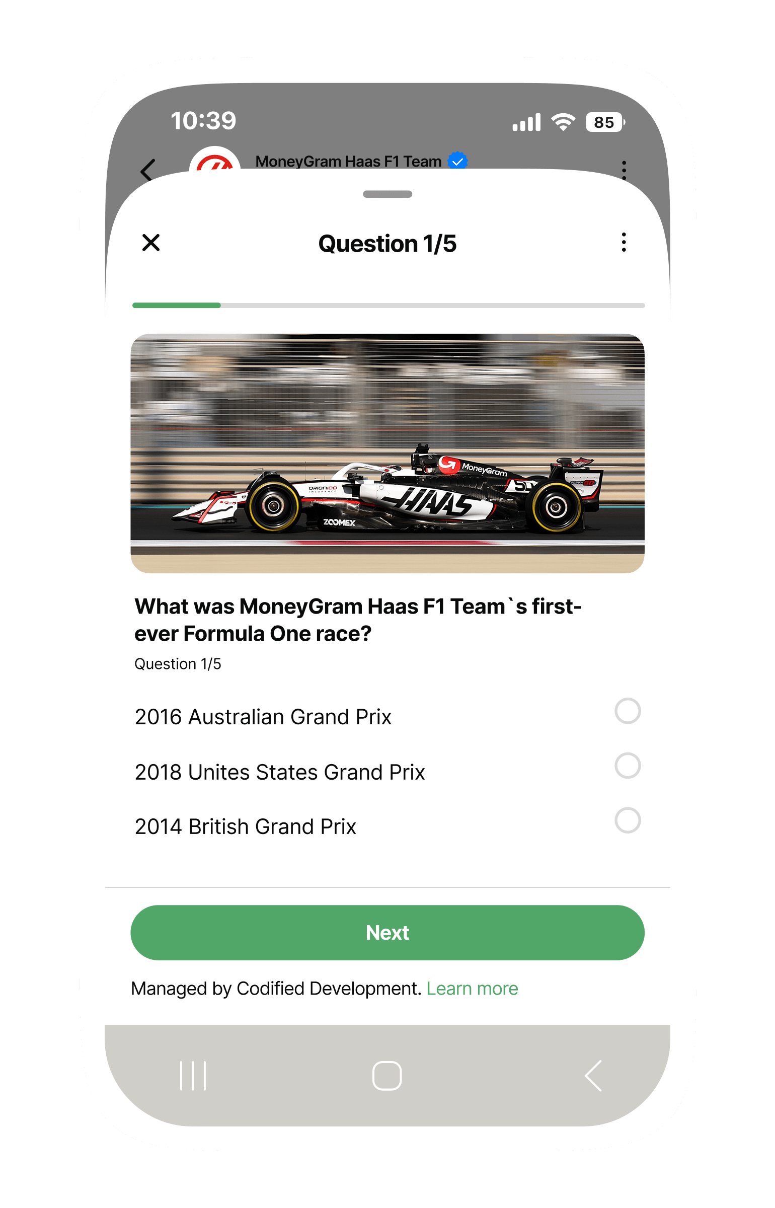 Mobile phone screen showing a WhatsApp-style quiz titled ‘Question 1/5’. A progress bar near the top is slightly filled. Below it is an action photo of a MoneyGram Haas F1 car racing on track. The multiple-choice question reads: ‘What was MoneyGram Haas F1 Team’s first-ever Formula One race?’ with three answer options listed vertically: ‘2016 Australian Grand Prix,’ ‘2018 United States Grand Prix,’ and ‘2014 British Grand Prix,’ each with an empty radio button. At the bottom is a large green ‘Next’ button and a note stating the quiz is managed by Codified Development.