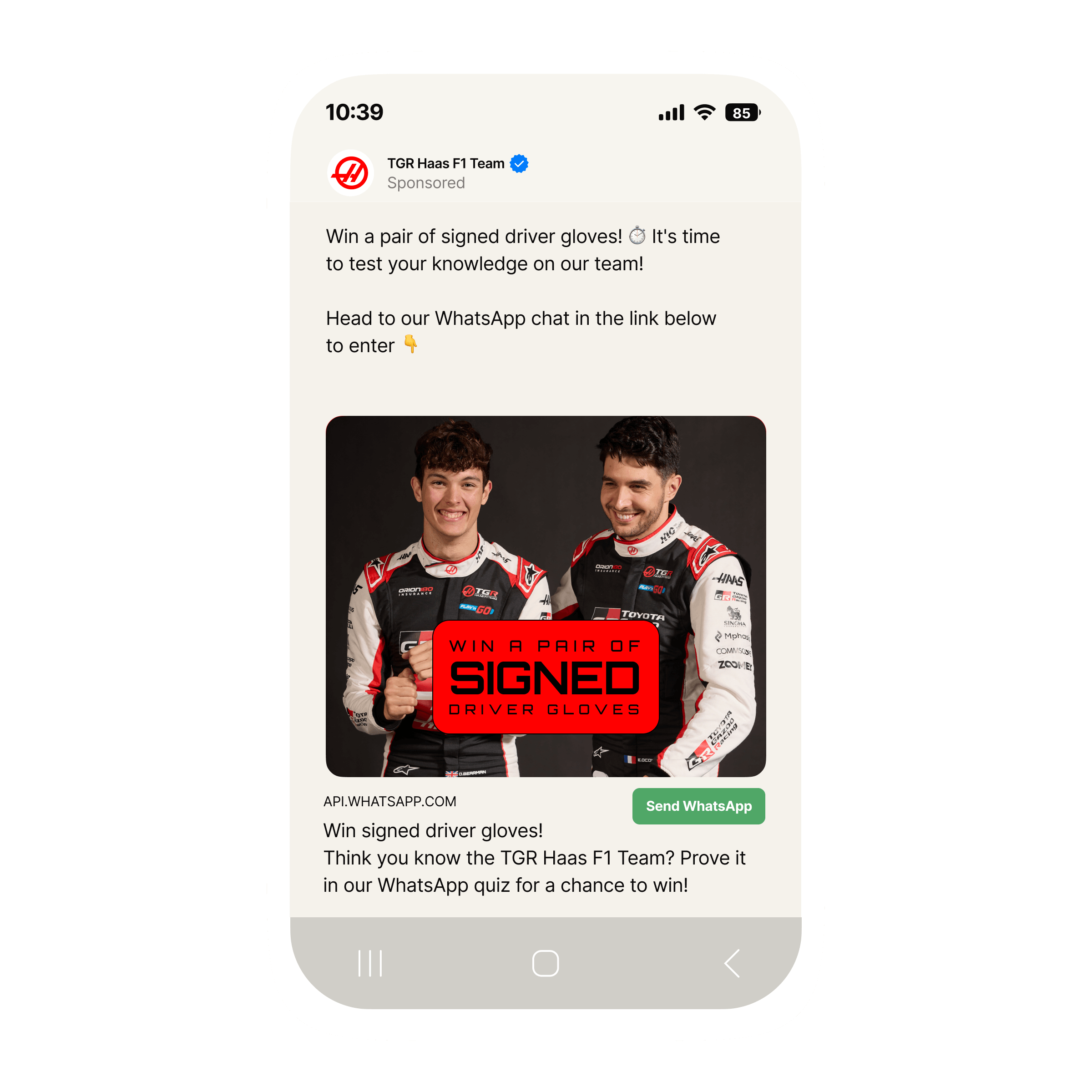 Mobile phone screen showing a sponsored Facebook post from the TGR Haas F1 Team promoting a WhatsApp quiz. The post invites users to ‘Win a pair of signed driver gloves’ by testing their knowledge of the team. Below the text is a red banner image featuring two Haas F1 drivers in black and red racing suits with sponsor logos, standing side by side. Over the banner is a bold black box with white text that reads ‘Win a pair of signed driver gloves.’ At the bottom of the post there is a button labeled ‘Send WhatsApp’ to enter the quiz.