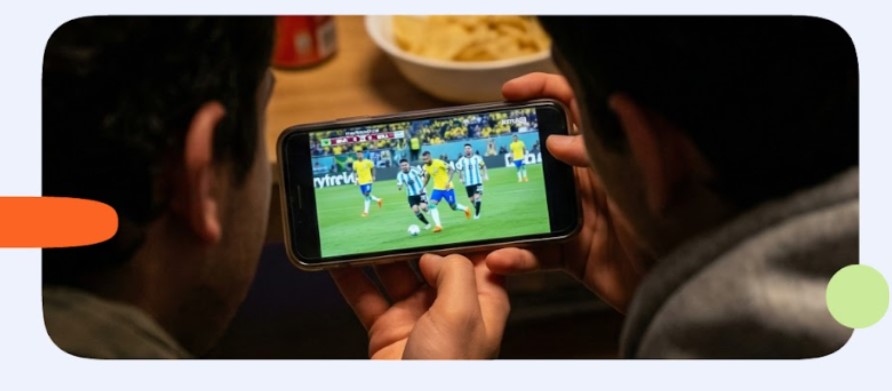 Imagen de dos hombres viendo un partido de fútbol en el smartphone.