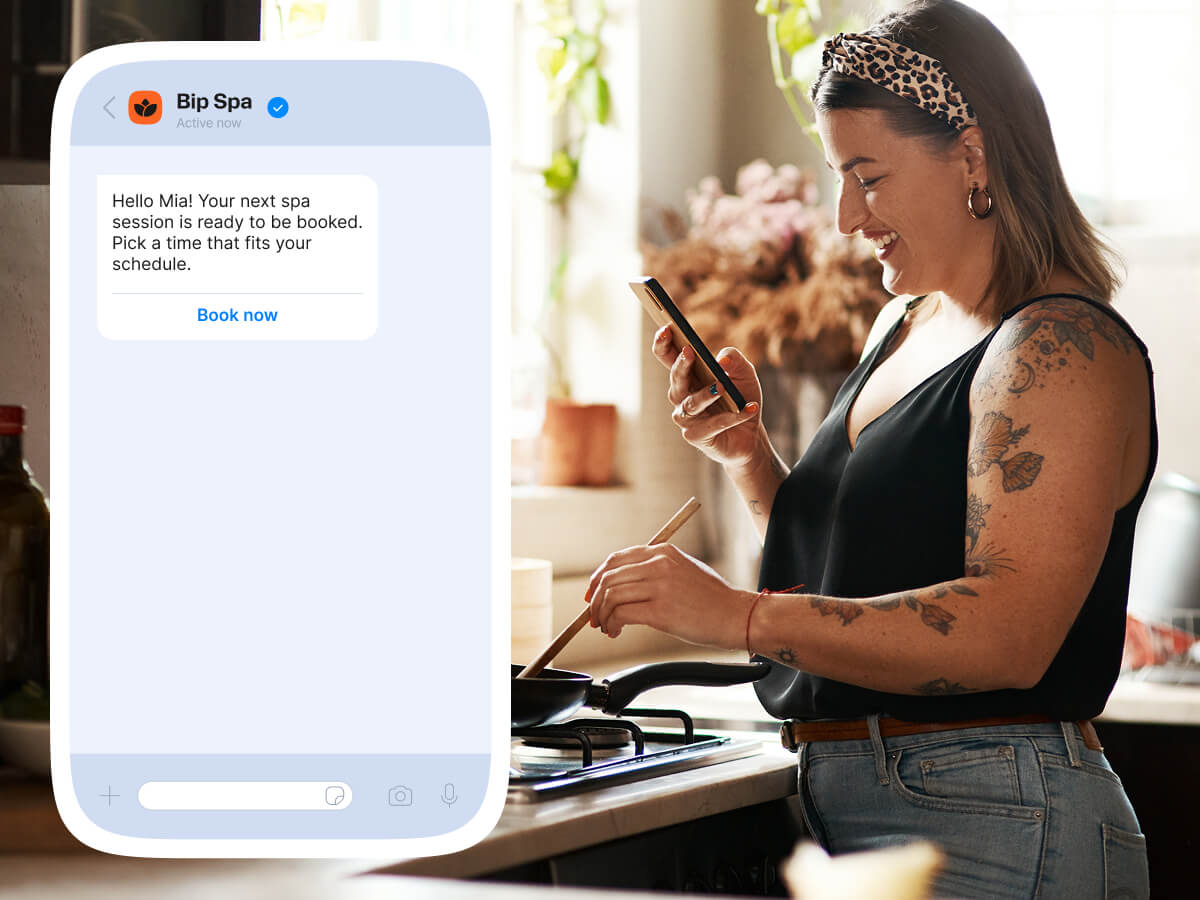 Woman receiving spa appointment booking message on smartphone while cooking at home