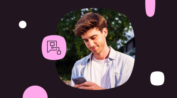 Smiling man with brown hair looking down at his smartphone outdoors with greenery in the background. The photo is on a dark plum background with pink accent shapes and a chat/media messaging icon.