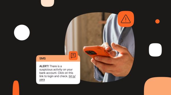 Close-up of a person using a phone beside an SMS alert that reads, “ALERT! There is a suspicious activity on your bank account. Click on this link to login and check. bit.ly/yara,” with a warning icon above.