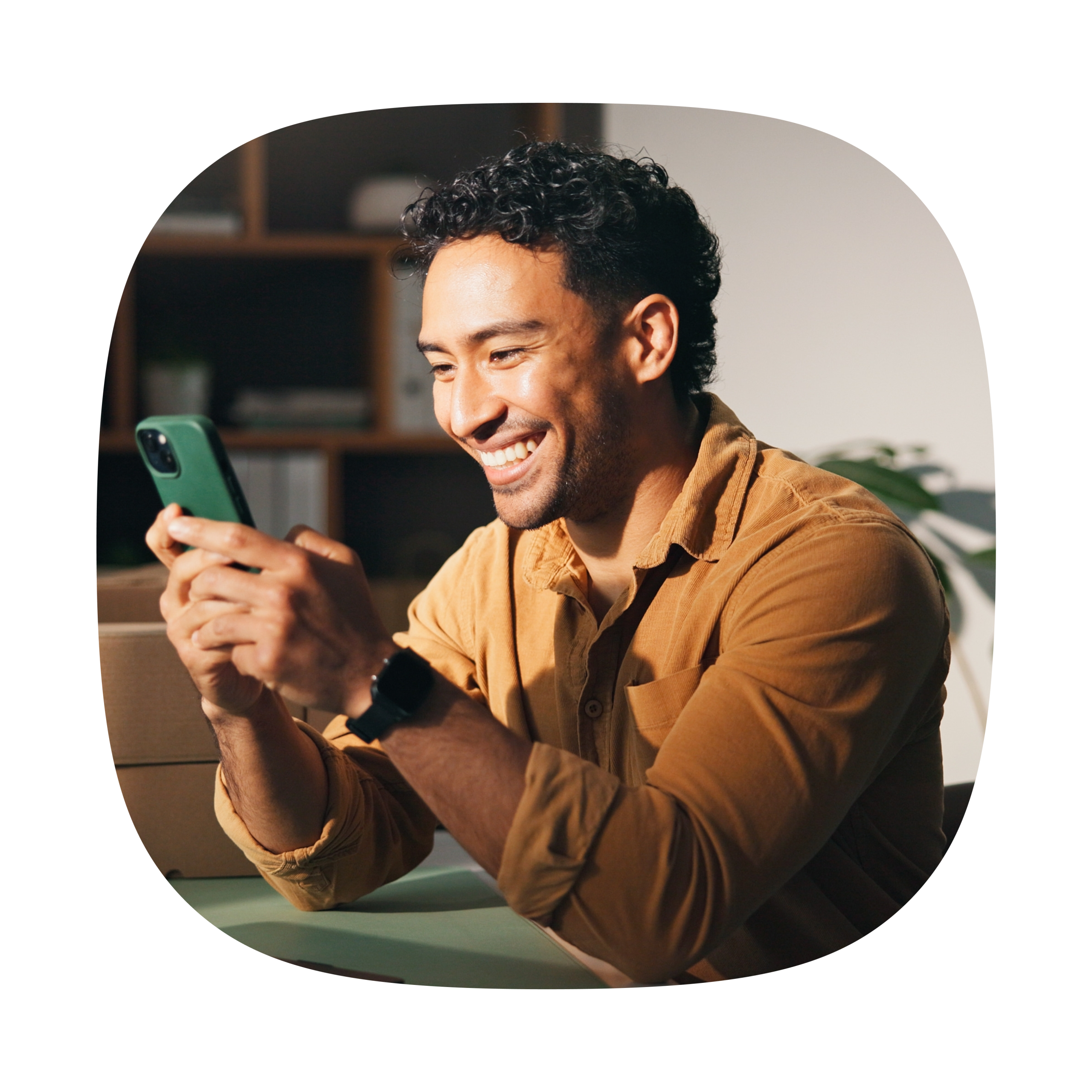 Man sitting on couch looking at his phone happily