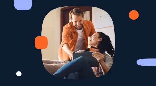 A couple looks at a tablet while holding a payment card at home.