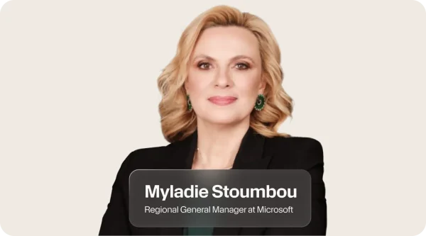 Myladie Stoumbou, Regional General Manager at Microsoft, smiling softly in a black blazer with shoulder-length blonde wavy hair and green earrings. Her portrait sits at the center of a light graphic and a label beneath shows her name and title.