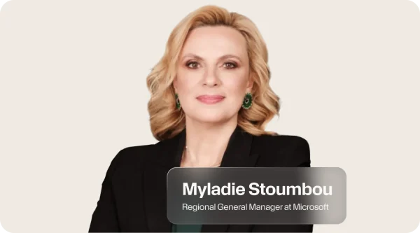 Myladie Stoumbou, Regional General Manager at Microsoft, smiling softly in a black blazer with shoulder-length blonde wavy hair and green earrings. Her portrait sits at the center of a light graphic and a label beneath shows her name and title.