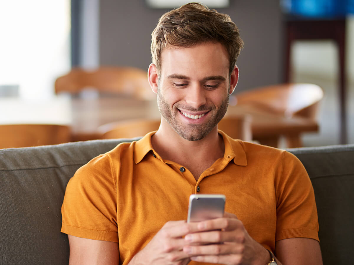 Man sitting on a couch and looking at his smartphone.