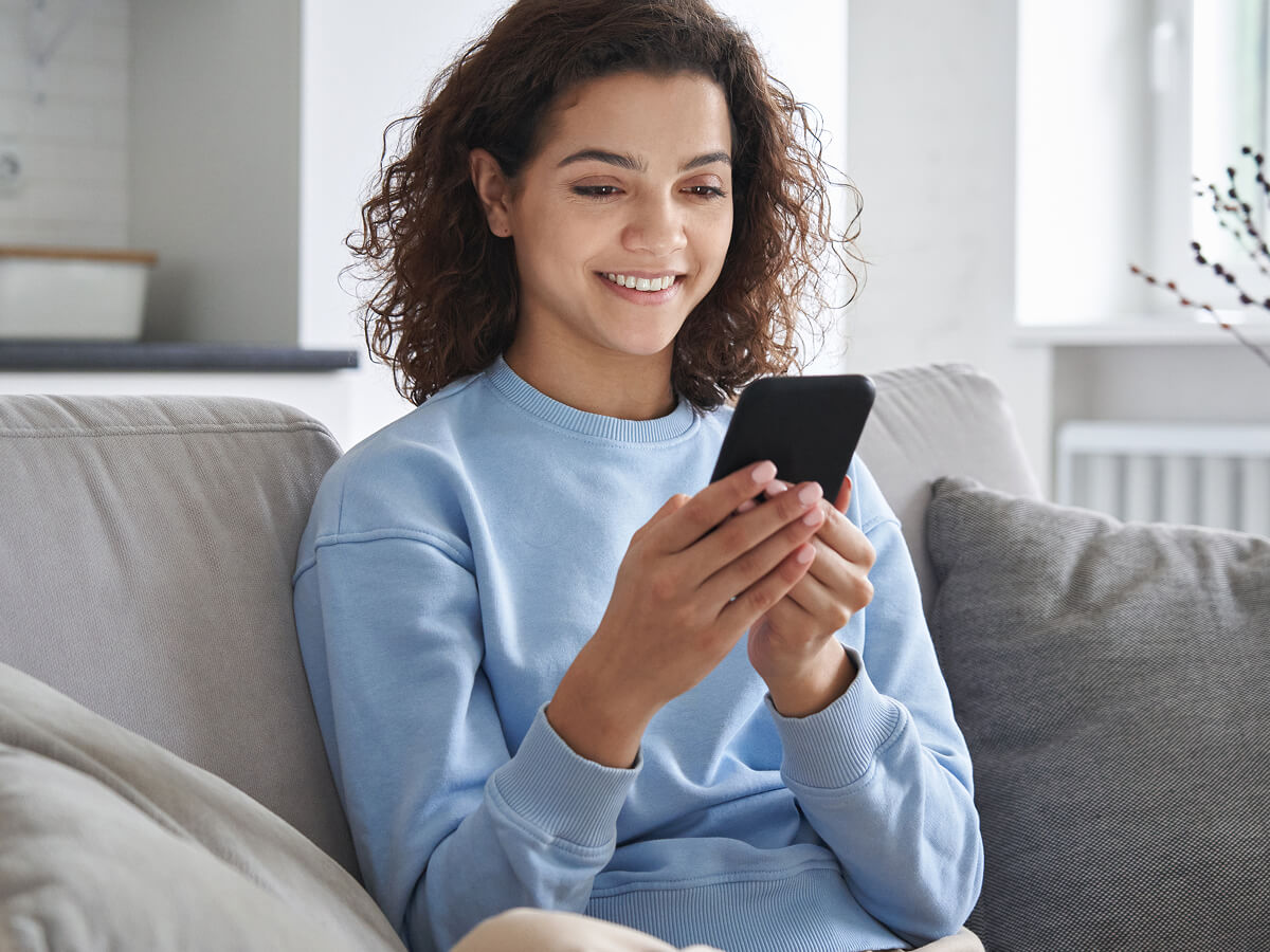 Woman sitting on a sofa and using a smartphone.