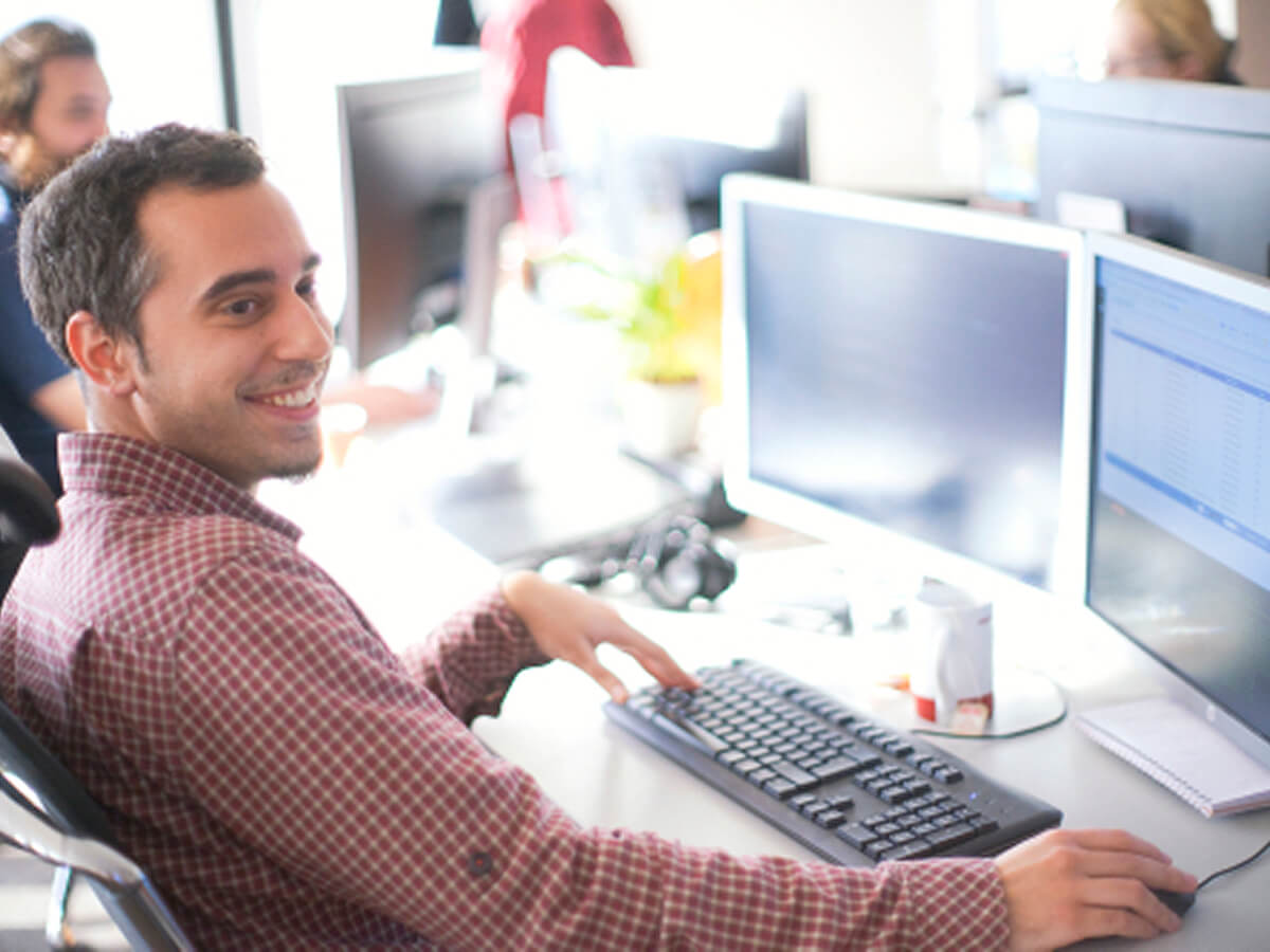 Employee working at a dual‑monitor workstation in a bright open office environment